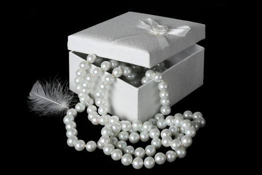 Gift box with string of white pearls and a white feather