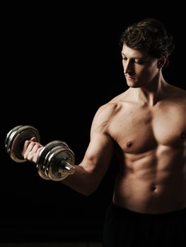 Photo of a man in his early thirties doing bicep curls with a dumbbell over a black background.