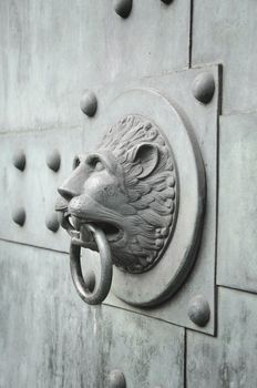 vertically oriented photo of a lion head shaped ancient door knocker