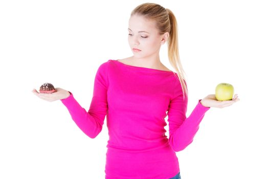 Young casual woman holding an apple and cookie. Isolated on white.