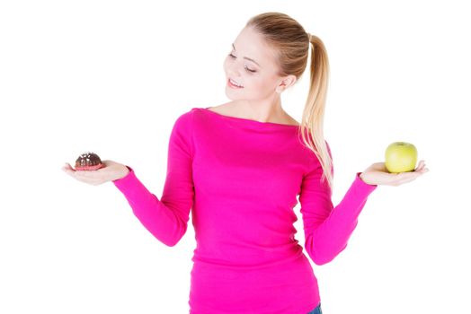 Young casual woman holding an apple and cookie. Isolated on white.