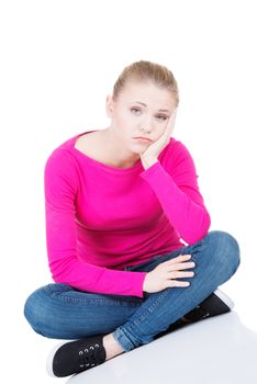 Young sad woman sitting. Isolated on white.