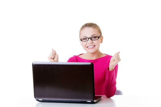 Young happy woman sitting in front of laptop. Isolated on white.