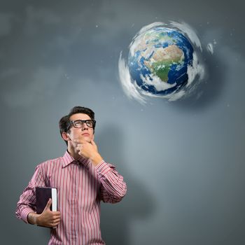 young man with a book thinks. it over planet Earth with clouds. an image of NASA.