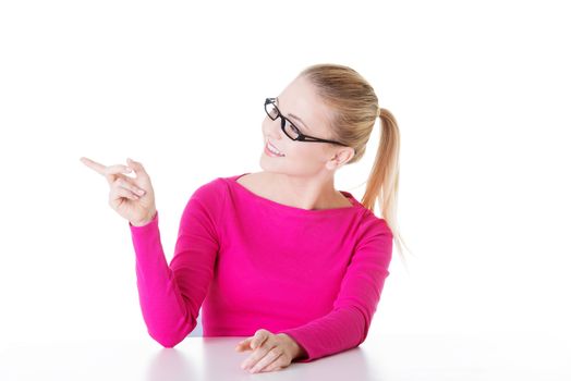 Young casual woman pointing aside. Isolated on white.