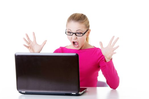 Young surprised woman sitting in front of laptop. Isolaed on white.