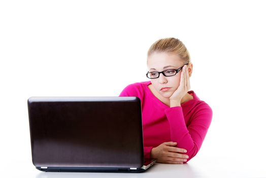 Bored, sad woman sitting in front of laptop. Isolated on white.