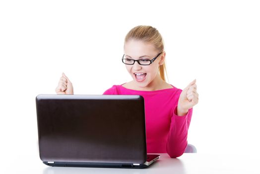 Young happy woman sitting in front of laptop. Isolated on white.