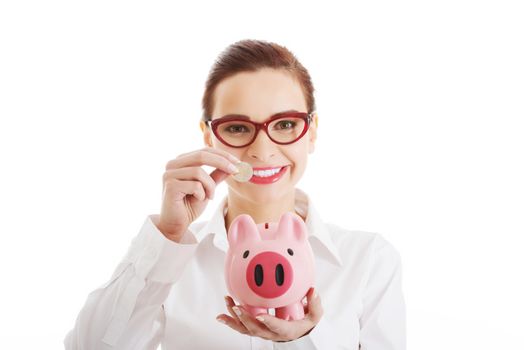 Beautiful business woman with coin and piggy- bank. Isolated on white.