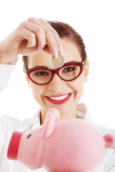 Beautiful business woman with coin and piggy- bank. Isolated on white.