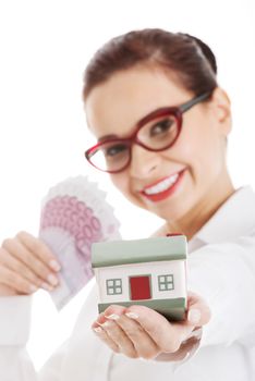 Beautiful business woman holding money and small house. Isolated on white.