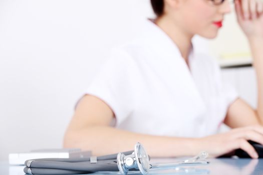 Young doctor sitting with stethoscope. Focus on the stethoscope.