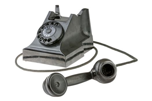 Retro dial-up rotary telephone with the handset lying in the foreground turned towards the camera on a white studio background