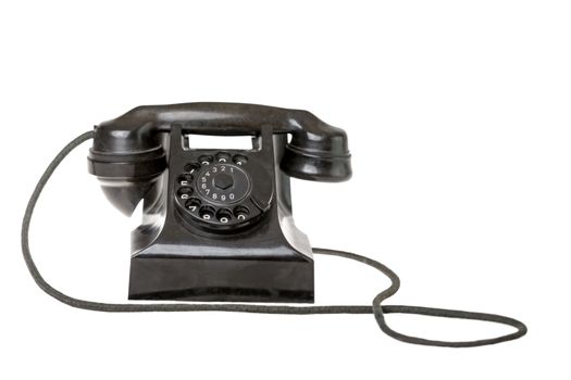 Old-fashioned black rotary telephone instrument with its handset on the cradle on a white background with a reflection and copyspace