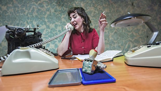 young Secretary smoking a cigarette while talking on the phone, 1960's scene