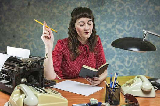 secretary in the office with a pencil in the hand looks at its notebook, 1960's scene