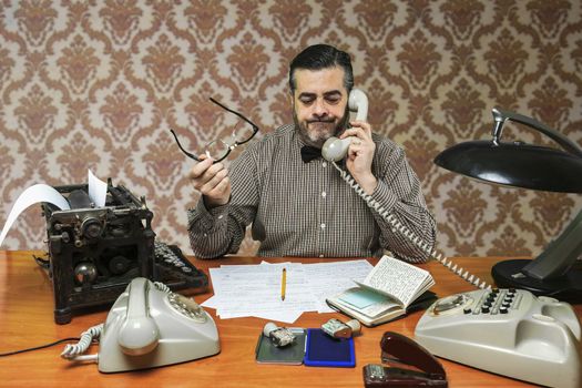 Employee with glasses talking on the phone in the office in the 1960s