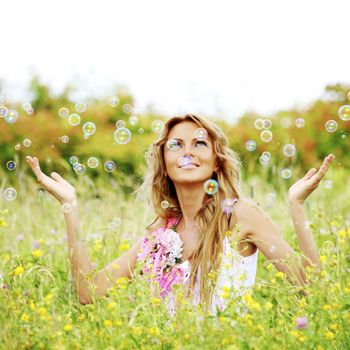Woman playing with soap bubbles on flower field