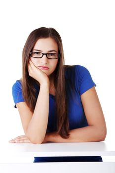 Young student woman bored, sitting by the desk. Isolated on white.