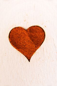 Heart shape made from spice on a wooden spoon. Composition.