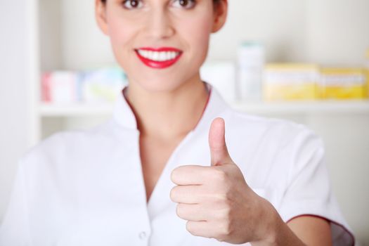 Young nurse, doctor showing ok gesture. Over indoor background.