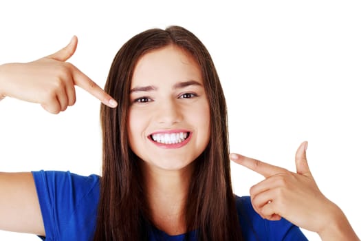 Beautiful woman pointing on her perfect white teeth. Isolated on white.