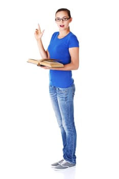 Young casual student woman with book and pointing up. Isolated on white.