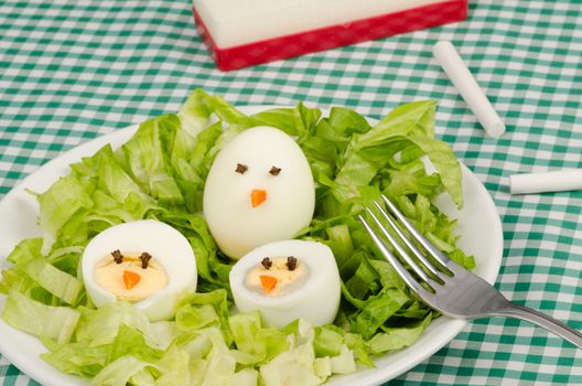 A salad served with decorated eggs, a kid meal