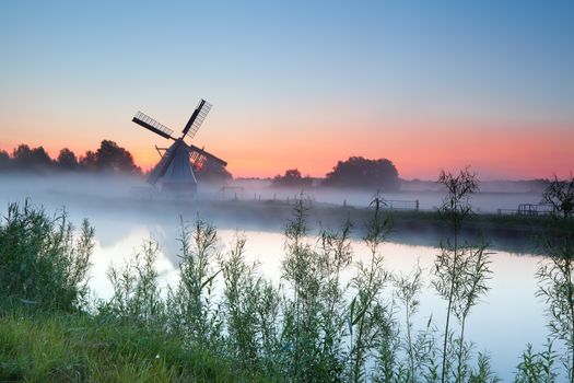 Dutch white windmill by river at sunrise, Groningen, Netherlands
