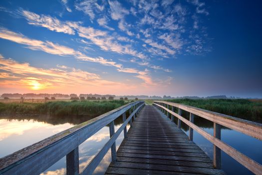 wooden bridge over river at summer sunrise