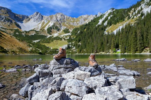 female leather hiking shoes on rock by Alpine lake, Bavaria, Germany