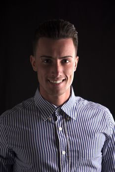 Smiling young man in striped shirt, looking at camera, isolated on black
