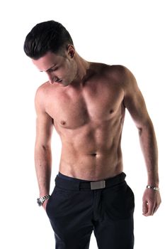 Handsome, fit young man shirtless with black pants, isolated on white, looking down