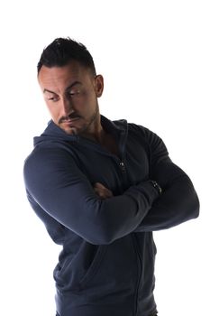 Muscular man with sweatshirt, arms crossed on his chest, looking down, isolated on white