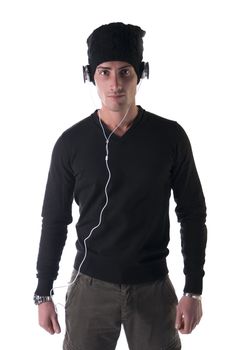 Attractive young man with black wool hat and sweater, listening to music on headphones