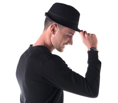 Profile shot of young man smiling, touching fedora hat on his head, isolated on white