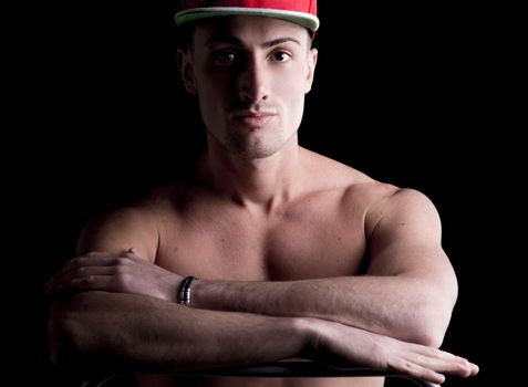 Smiling handsome young man shirtless, arms crossed on bare chest, isolated on black