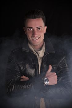 Attractive young man with white sweater and black leather jacket. Smoke and dark background