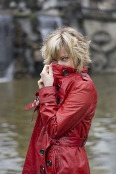 Attractive young woman with red leather jacket in front of big fountain