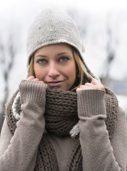 Attractive blonde young woman with wool hat, holding scarf with her hands