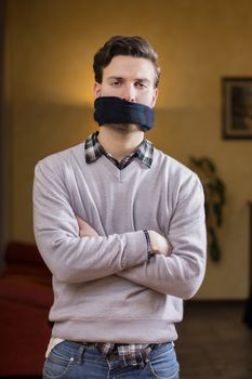 Young man with gag (scarf) on his mouth cannot speak
