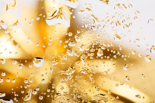 golden abstract background with water drops on glass with gold ribbon in background 