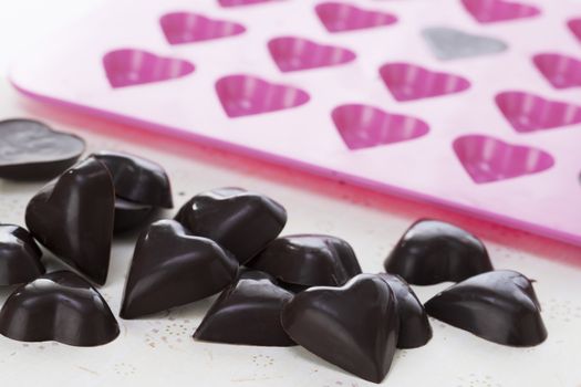 Dark chocolate hearts in with heart form in background