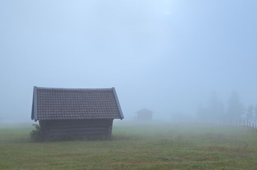 old wooden hut in dense fog on Alpine meadow, Germany