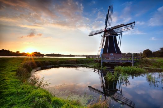 charming Dutch windmill reflected in lake at sunset, Holland