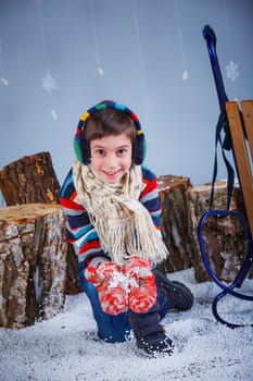 Winter Fashion. Adorable happy fashion boy in winter hat gloves and sweater in studio.