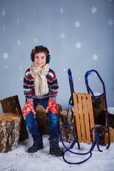 Winter Fashion. Adorable happy fashion boy in winter hat gloves and sweater in studio.