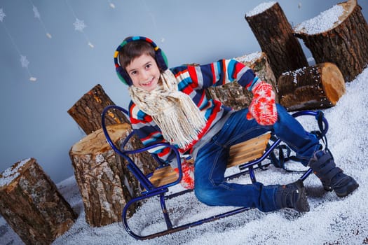 Winter Fashion. Adorable happy fashion boy in winter hat gloves and sweater in studio.
