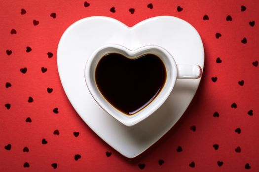 Coffee cup in shape of heart on red paper background. Top view