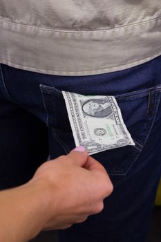 Thief takes out a dollar out of the pocket